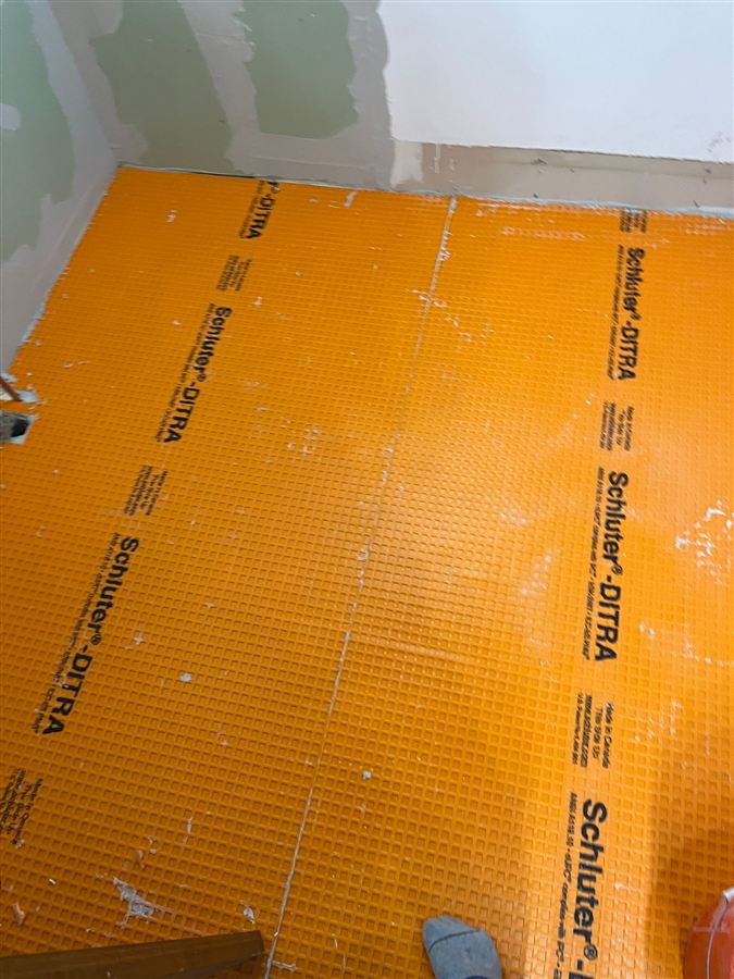 Orange waterproofing membrane laid over a prepared floor